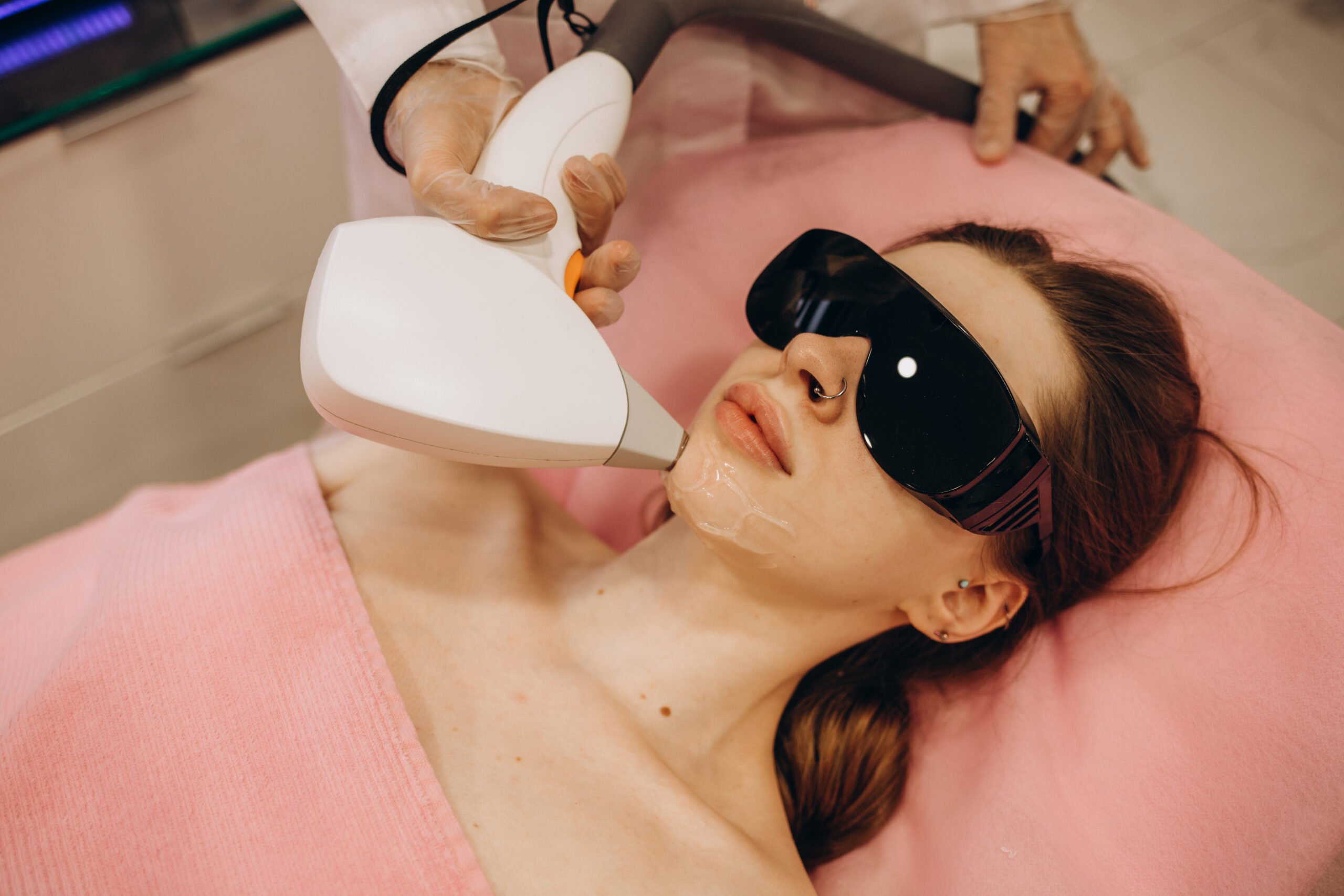 Beautiful woman having her facial hair removed by female beautician. Lazer epilation treatment, at clinic